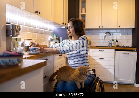 Frau im Rollstuhl in der Küche zu Hause Stockfoto
