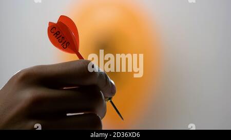 Hand hält Dart mit Krise Wort. Stockfoto
