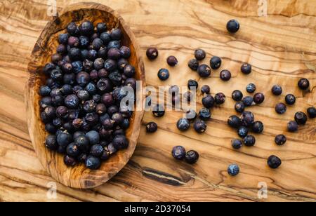 Getrocknete Wacholderbeeren auf Olivenholz Stockfoto