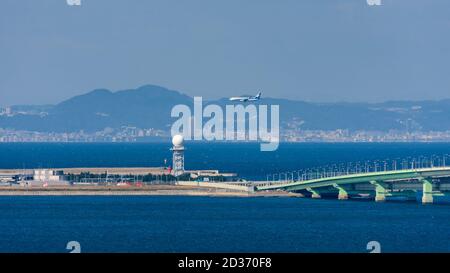 Osaka / Japan - 16. November 2017: ANA-Flugzeug landet auf dem Kansai International Airport, einer künstlichen Insel in der Bucht von Osaka, mit der Stadt Kobe visibl Stockfoto