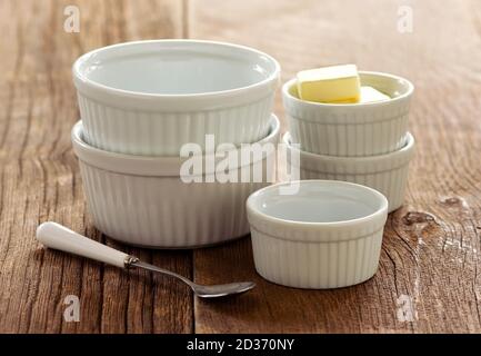 Butterwürfel in weißen Ramekins auf Holz-Tischplatte. Stockfoto
