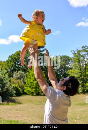 Mann wirft glückliches Baby in die Luft Stockfoto