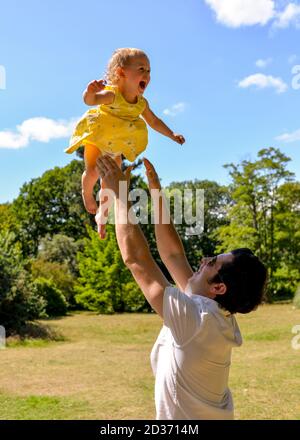 Mann wirft glückliches Baby in die Luft Stockfoto