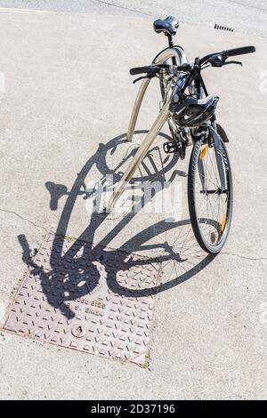 Fahrrad und Radfahrer Helm geparkt, gesperrt an einem Fahrradständer mit Schatten auf dem Bürgersteig, Kill, County Kildare, Irland Stockfoto