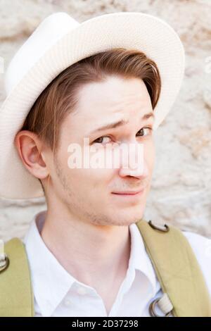 Der junge Kaukasusmann mit weißem Hut lächelt die Kamera an. Nahaufnahme Stockfoto