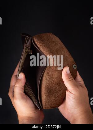 Hände eines Mannes, der eine leere Brieftasche auf einem dunklen Hintergrund hält Stockfoto