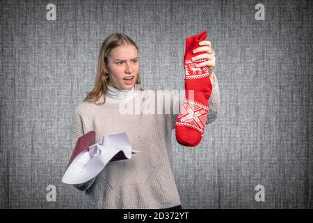 Eine enttäuschte junge Frau hält ihr Geschenk hoch Stockfoto
