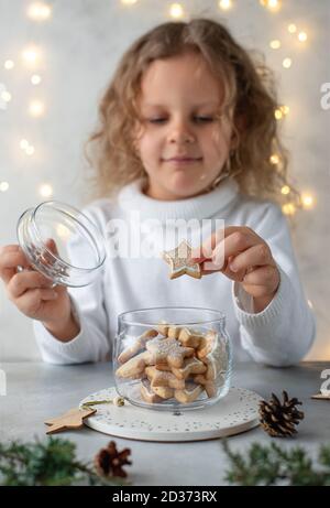 Nettes kleines Mädchen, das Weihnachtskekse aus einem Glas herausnimmt Glas Stockfoto