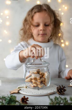 Niedliches kleines Mädchen, das ein Glas Weihnachtskekse öffnet Stockfoto