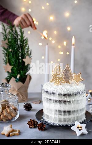Köstliche Weihnachtskuchen und Frauenhände zünden Kerzen Stockfoto