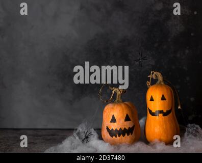 Halloween Kürbisse mit bemalten Gesichtern und Spinnennetz mit hängenden Spinnen Stockfoto