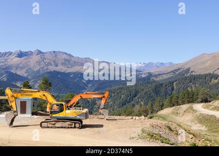 Bagger in einem Bergtal an einem sonnigen Tag geparkt. Bau einer Skipiste. Stockfoto