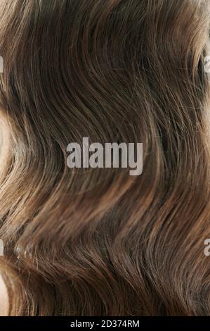Brunette Haare Hintergrund. Lange lockige Haarstruktur Stockfoto