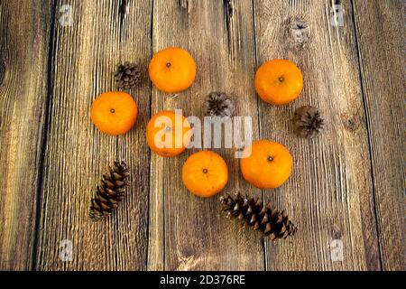 Mandarinen und Zapfen isoliert auf dem Holzhintergrund Neujahr Und Weihnachtskonzept Stockfoto