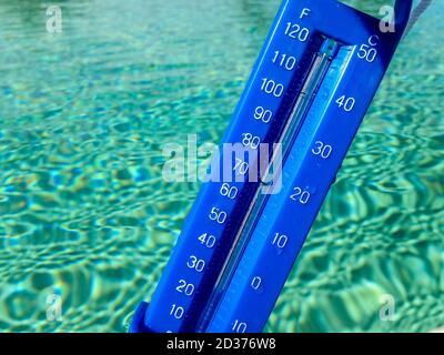 Nahaufnahme eines blauen Thermometers in der Nähe von Poolwasser Stockfoto