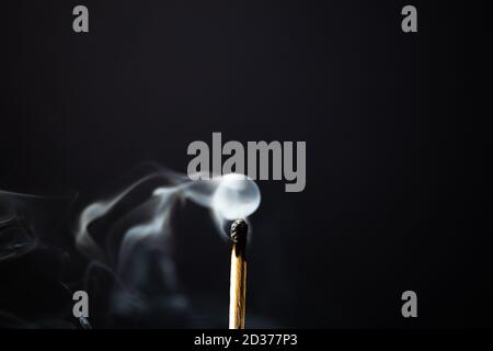 Unbeleuchtetes Holzmatch, das Rauch mit schwarzem Hintergrund abgibt Stockfoto