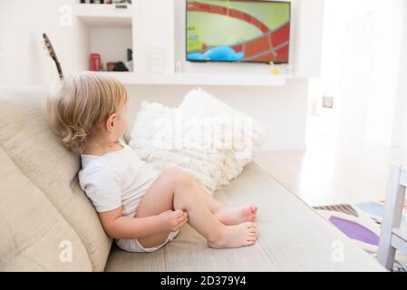 Niedlichen Baby junge sitzen und beobachten Cartoons. Stockfoto