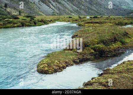 Herbstlandschaft mit azurblauem milchigen Gebirgsfluss und üppiger Vegetation. Stimmungsvolle Herbst alpine Landschaft mit milchigen Fluss mit klarem Cyan Wasser. Grasse Stockfoto