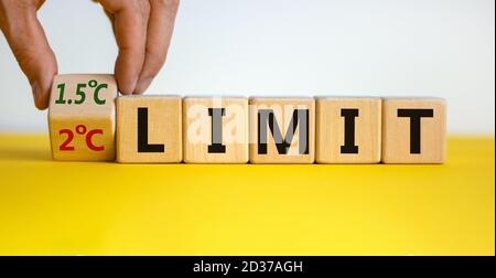 Symbol für die Begrenzung der globalen Erwärmung. Männliche Hand dreht den Würfel und ändert den Ausdruck '2 C Limit' auf '1.5 C Limit' oder umgekehrt. Schöne gelbe t Stockfoto