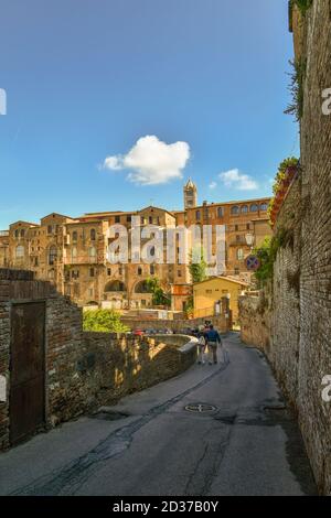 Via Fosso di Sant'Ansano, die hinter dem ehemaligen Krankenhaus von Santa Maria della Scala, mit dem Glockenturm der Kathedrale von Siena, Toskana, Italien läuft Stockfoto