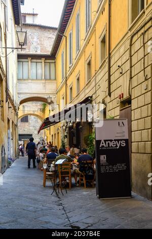 Touristen, die in einem Restaurant im Freien in der Via di Beccheria, dem historischen Zentrum von Siena, UNESCO-Weltkulturerbe, Toskana, Italien zu Mittag essen Stockfoto