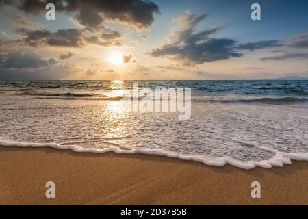 Eine Sunset Ocean Wave bricht an der Küste mit der Sonne am Ocean Horizon Stockfoto