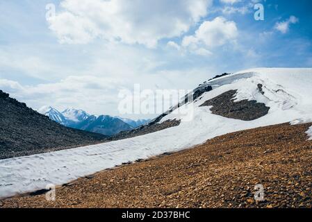 Wunderbarer Blick auf kleinen Gletscher auf steinigen Hügel unter blauem Himmel mit Wolken. Schöne alpine Landschaft mit Eiskiefel auf Felsen. Farbenfrohe Bergkulisse Stockfoto