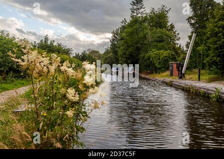 Altes Hebezeug, das am Montgomery-Kanal steht. Ein paar Narrowboote liegen an der alten Uferstraße. Stockfoto