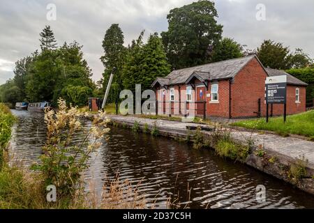 Altes Hebezeug, das am Montgomery-Kanal steht. Ein paar Narrowboote liegen an der alten Uferstraße. Stockfoto