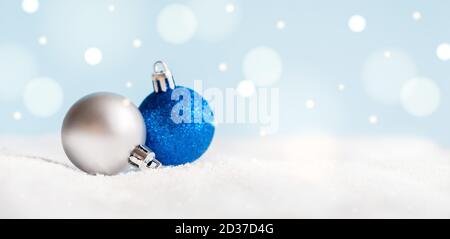 Weihnachtskugeln auf der Oberfläche mit Schnee und defokussierte Lichter mit Kopierraum. Stockfoto