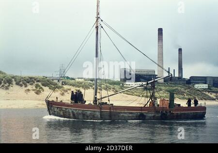 Das Fischerboot "Shamrock" passiert das Kohlekraftwerk von Hayle auf seinem Weg vom Hafen von Hayle in Cornwall hinunter. Foto aufgenommen in der 1960' Stockfoto