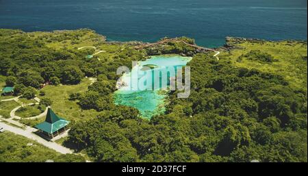 Indonesiens Wahrzeichen des Salzwasser Jade Lake Weekuri auf Sumba Island. Episches Resort am Limpid loch mit natürlicher Vielfalt. Erstaunliche Architektur Attraktion mit Straße und Autos an grünen tropischen Pflanzen, Bäume Stockfoto