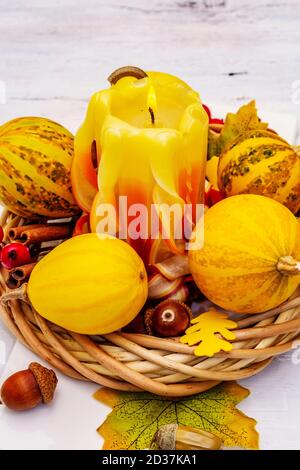 Herbstkomposition für Thanksgiving oder Halloween. Brennende geschnitzte Kerze, reife Kürbisse, Eicheln, Herbstblätter und Hagebutten. Weiße Holzbretter b Stockfoto