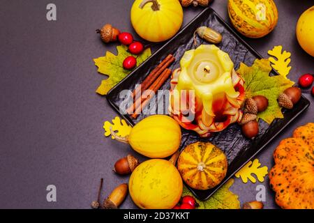 Herbstkomposition für Thanksgiving oder Halloween. Brennende geschnitzte Kerze, reife Kürbisse, Eicheln, Herbstblätter und Hagebutten. Steinbeton hintergr Stockfoto