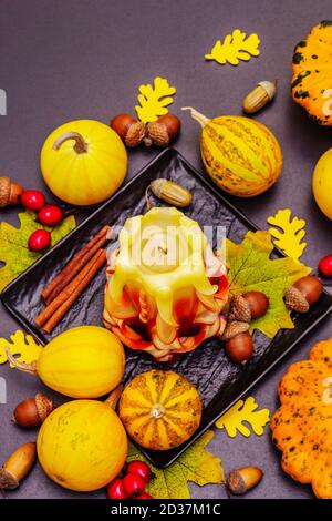 Herbstkomposition für Thanksgiving oder Halloween. Brennende geschnitzte Kerze, reife Kürbisse, Eicheln, Herbstblätter und Hagebutten. Steinbeton hintergr Stockfoto