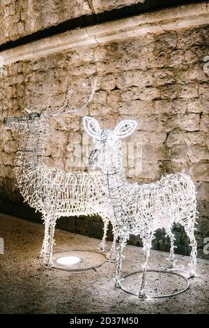 Die Figur des Weihnachtshirsches ist ein Metallrahmen mit einer weißen Girlande bedeckt. Dekoration der Straßen der Stadt für das neue Jahr. Stockfoto