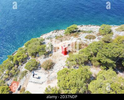 Roter Leuchtturm auf der Klippe über dem Meer und das kleine Heiligtum in Rogoznica Bucht in Mitteldalmatien, Kroatien mit Drohne fotografiert Stockfoto