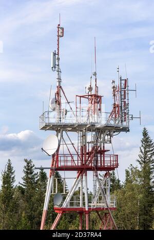 Rot-weißer Kommunikationsturm mit TV- und Mobilfunkantennen Stockfoto