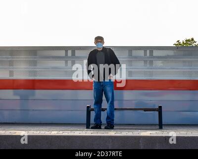 Moskau. Russland. Oktober 2020. Auf der Bahnhofsplattform steht ein einesiger Mann mit Rucksack in einer schützenden medizinischen Maske, der darauf wartet Stockfoto