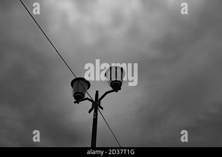 Altmodische beleuchtete Lampe gegen einen dunklen bewölkten Himmel gesetzt. Stockfoto