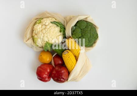 Gemüse im Öko-Beutel auf weißer Oberfläche. Pfeffer, Tomaten, Mais, Gurke, Brokkoli, Blumenkohl in wiederverwendbaren Shopping umweltfreundliche Baumwollstoff Taschen Stockfoto