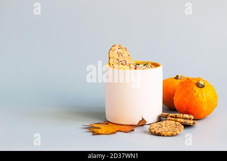 Kürbiscremesuppe mit Samen und Sahne in Keramikbecher und Multikorn gesunde Cracker auf blauem Hintergrund. Stockfoto