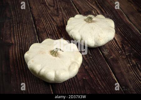 Zwei weiße Pattypan Squash auf dunklem Holzbrett Stockfoto