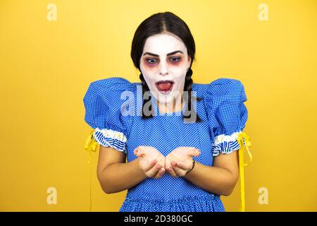 Frau trägt ein gruseliges Puppe halloween Kostüm über gelbem Hintergrund lächelnd mit Händen Handflächen zusammen erhalten oder geben Geste. Halt und Schutz Stockfoto