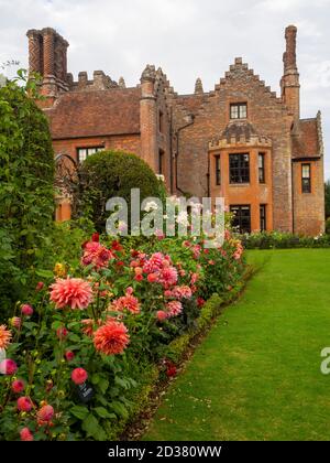 Wunderschöne Chenies Manor Gärten im September umgeben von lachsrosa Dahlien Blüten, 'Belle of Barmera', gekippten Eibenbäumen und Rosa 'Ballerina'. Stockfoto