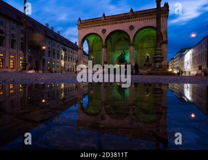 München, Deutschland. Oktober 2020. Die Feldherrnhalle am Odeonsplatz spiegelt sich in einer Wasserpfütze auf dem Boden wider. Der bayerische König Ludwig I. beauftragte den Architekten Friedrich von Gärtner mit dem Bau der Feldherrnhalle nach dem Vorbild der Loggia dei Lanzi in Florenz (Italien) in der bayerischen Hauptstadt. Die Bauzeit der bayerischen Kopie dauerte von etwa 1841 bis 1844, das Original wurde zwischen 1376 und 1382 gebaut. Kredit: Peter Kneffel/dpa/Alamy Live Nachrichten Stockfoto