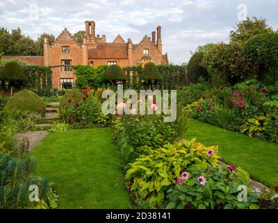 Chenies Herrenhaus in der Sonne; der versunkene Garten im September. Dahlia 'Creme de Cassis', 'Präferenz' und verschiedene Blattstrukturen und bunte Blüten. Stockfoto