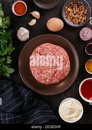 Frisches rohes Schweinefleisch in einer Holzschüssel mit Gemüse Im Hintergrund Stockfoto