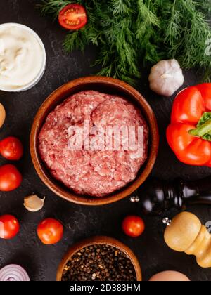 Frisches rohes Schweinefleisch in einer Holzschüssel mit Gemüse Im Hintergrund Stockfoto