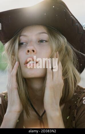 Nahaufnahme der Hippie-Frau im Cowboyhut bei Sonnenuntergang auf der Wiese. Stockfoto